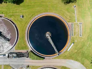 Luftaufnahme einer Kläranlage mit mehreren runden Becken zur Abwasseraufbereitung.